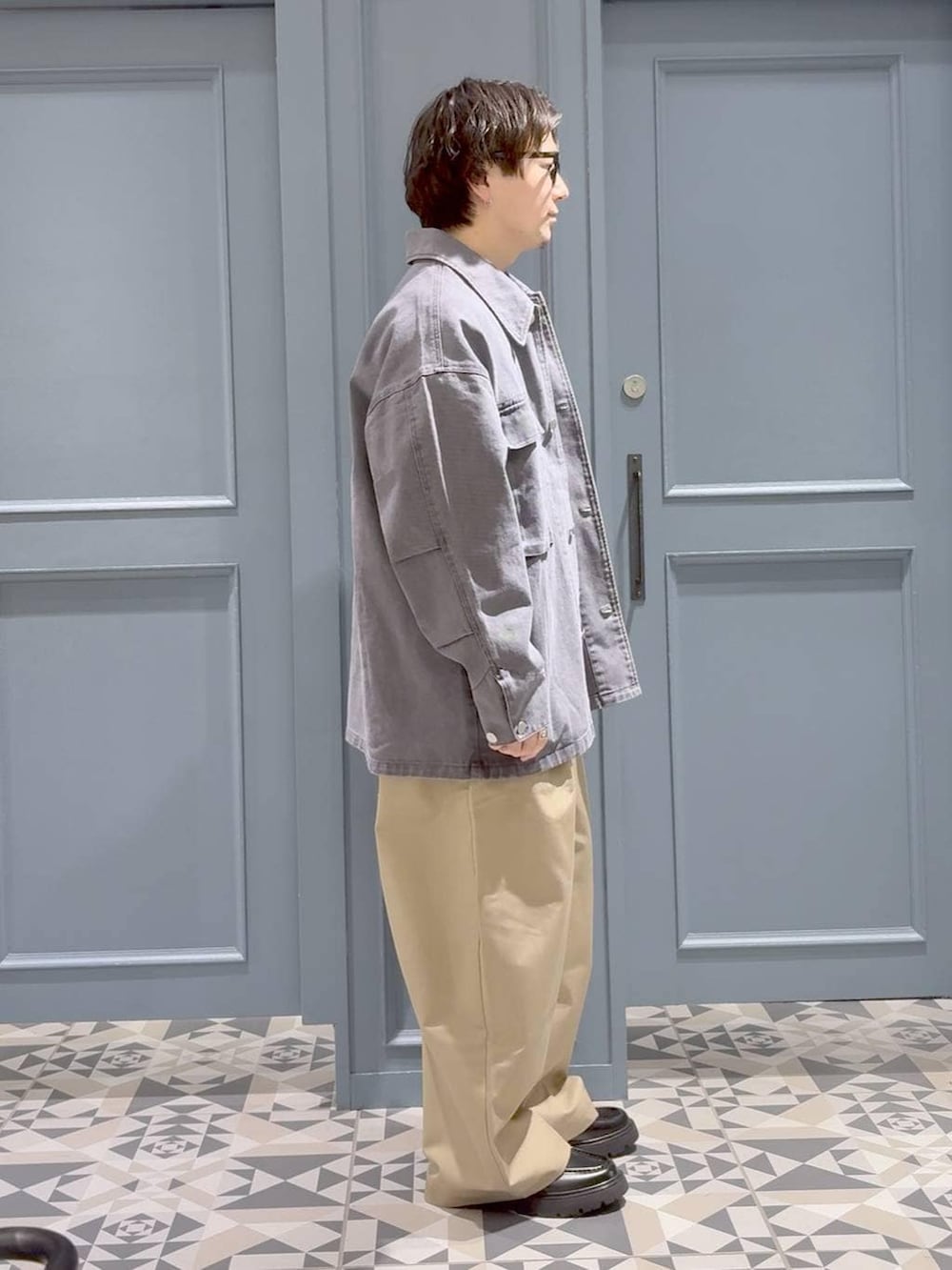 ブラック系のドレスシューズ、ベージュ系のチノパンツ、グレー系のミリタリージャケットを着用したメンズの春コーディネートの2枚目の写真