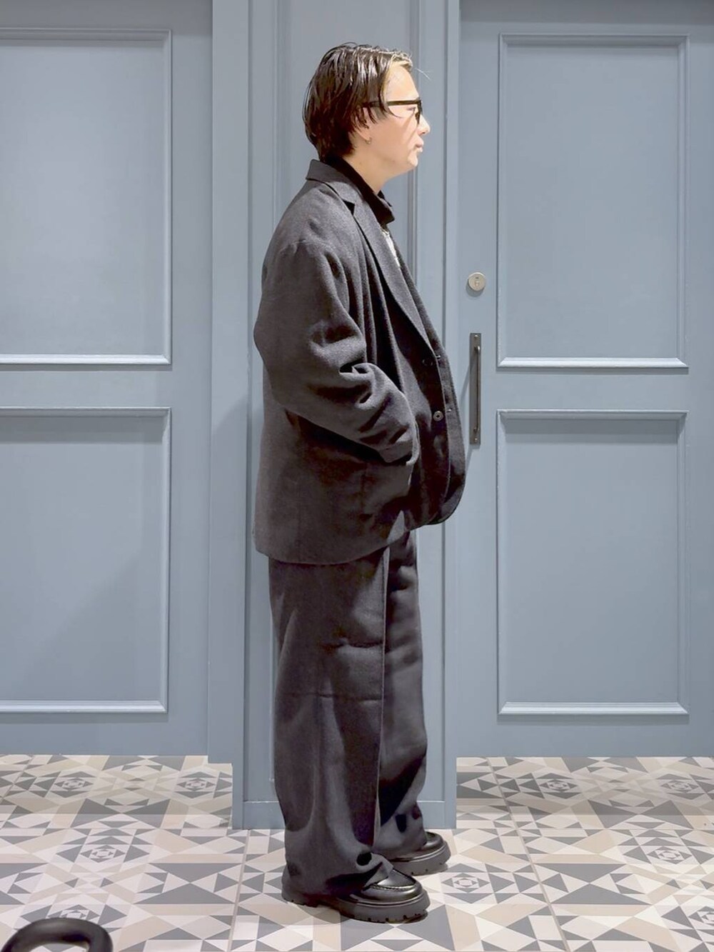 グレー系のニット/セーター、ブラック系のドレスシューズ、グレー系のテーラードジャケットを着用したメンズの秋コーディネートの2枚目の写真