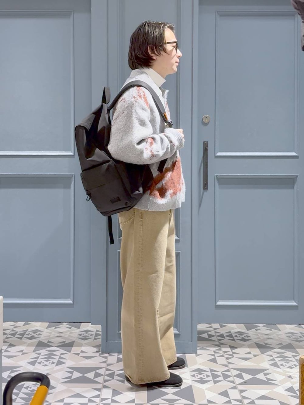 ベージュ系のデニムパンツ、ブラック系のバックパック/リュック、ホワイト系のTシャツ/カットソーを着用したメンズの冬コーディネートの2枚目の写真