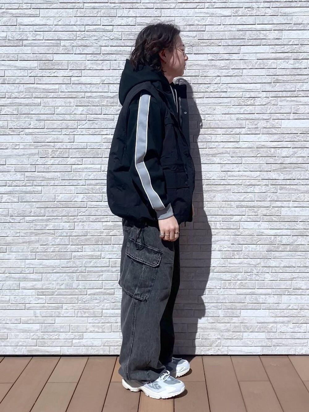 グレー系のデニムパンツ、ブラック系のナイロンジャケット、ブラック系のパーカーを着用したメンズの春コーディネートの2枚目の写真