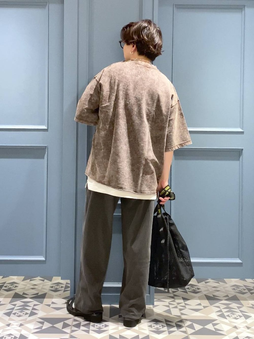 ブラウン系のTシャツ/カットソー、ブラック系のトートバッグ、ブラック系のサンダルを着用したメンズの春コーディネートの3枚目の写真