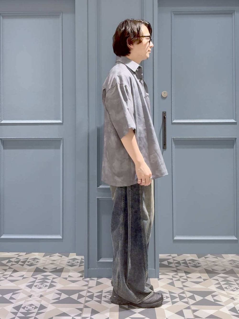 ブラック系のスニーカー、ブルー系のデニムパンツ、ブラック系のTシャツ/カットソーを着用したメンズの夏コーディネートの2枚目の写真