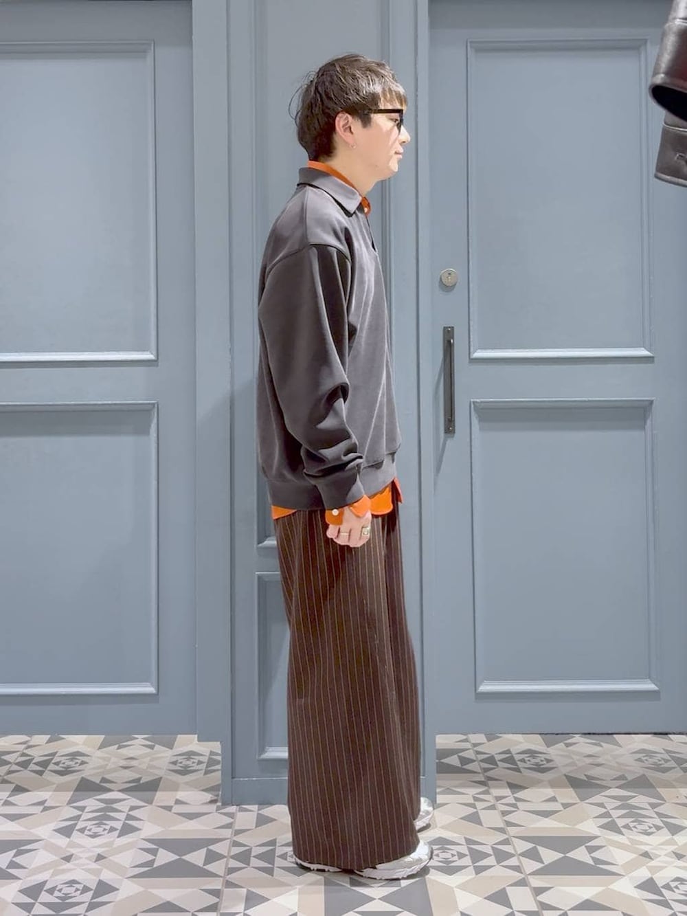 オレンジ系のシャツ/ブラウス、ブラウン系のスラックス、ブラック系のスウェットを着用したメンズの冬コーディネートの2枚目の写真