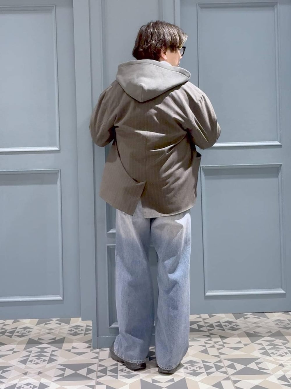 グレー系のテーラードジャケット、ブラック系のスニーカー、その他のパーカーを着用したメンズの春コーディネートの3枚目の写真