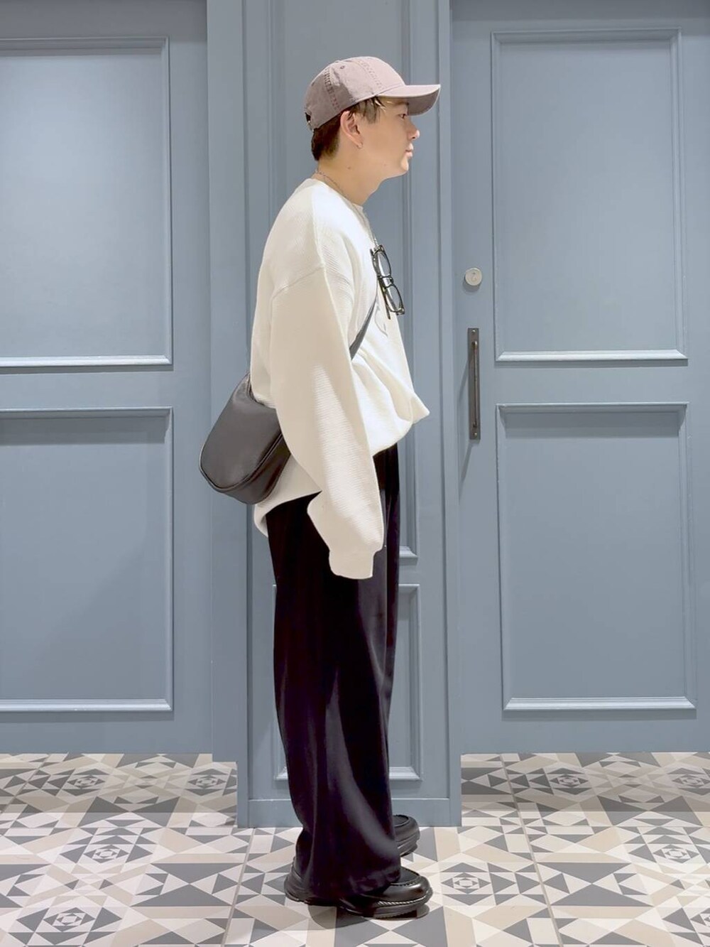 ブラック系のスウェットパンツ、ブラック系のショルダーバッグ、ブラック系のローファーを着用したメンズの秋コーディネートの2枚目の写真