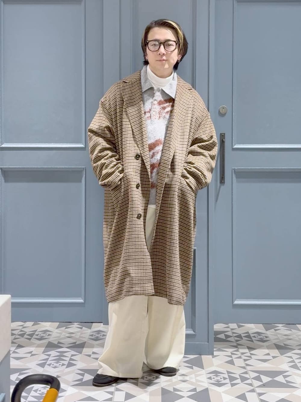 ブラウン系のチェスターコート、グレー系のポロシャツ、ホワイト系のスラックスを着用したメンズの冬コーディネートの4枚目の写真