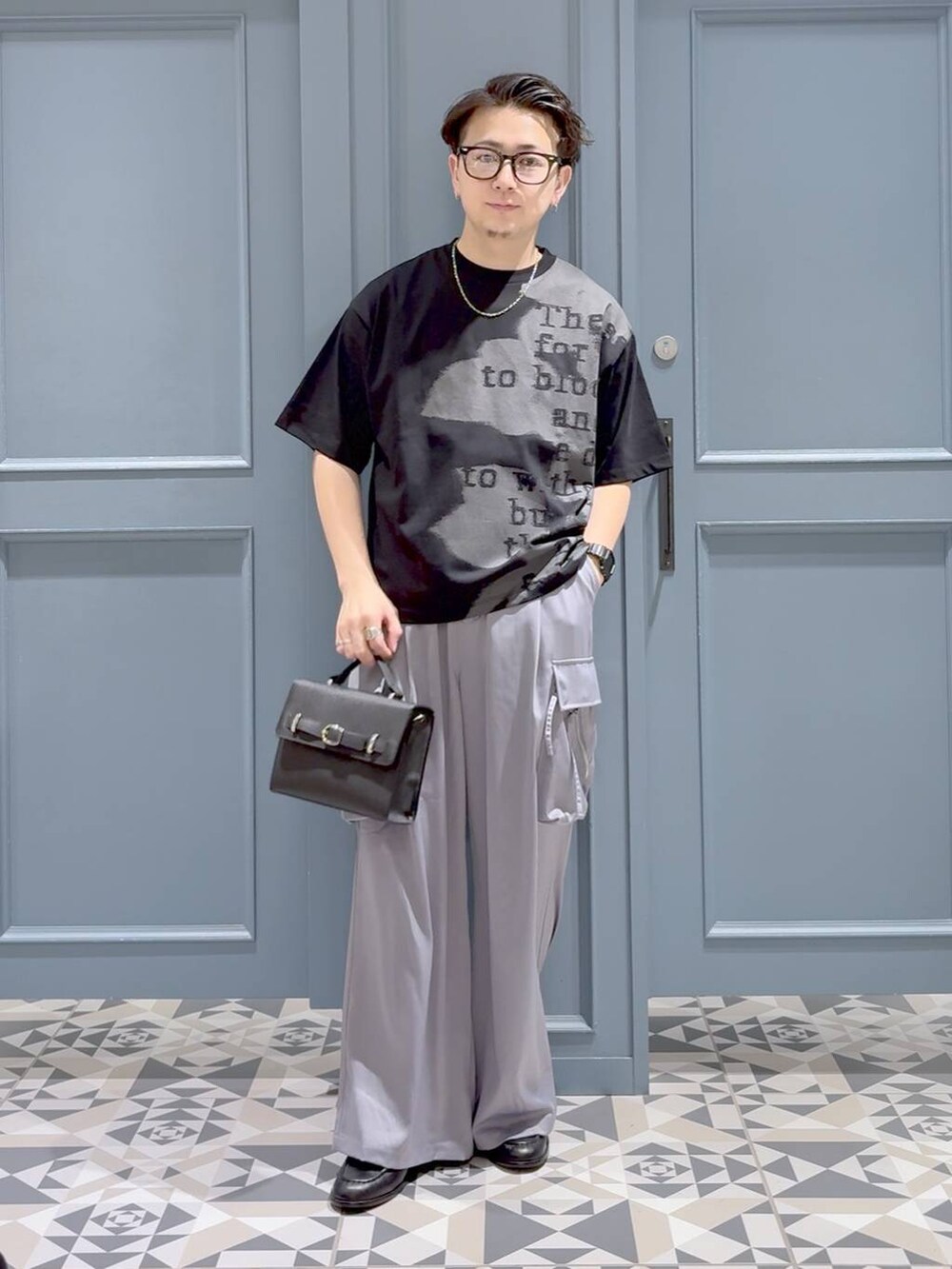 ブラック系のTシャツ/カットソー、ブラック系のローファー、ブラック系のショルダーバッグを着用したメンズの秋コーディネートの4枚目の写真