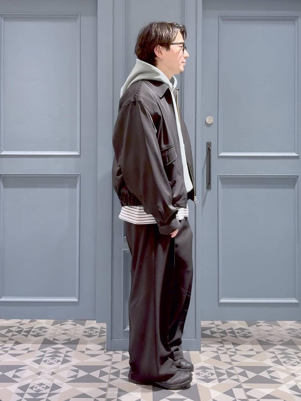 ブラック系のスニーカー、ブラック系のスラックス、グリーン系のパーカーを着用したメンズの春コーディネートの2枚目の写真