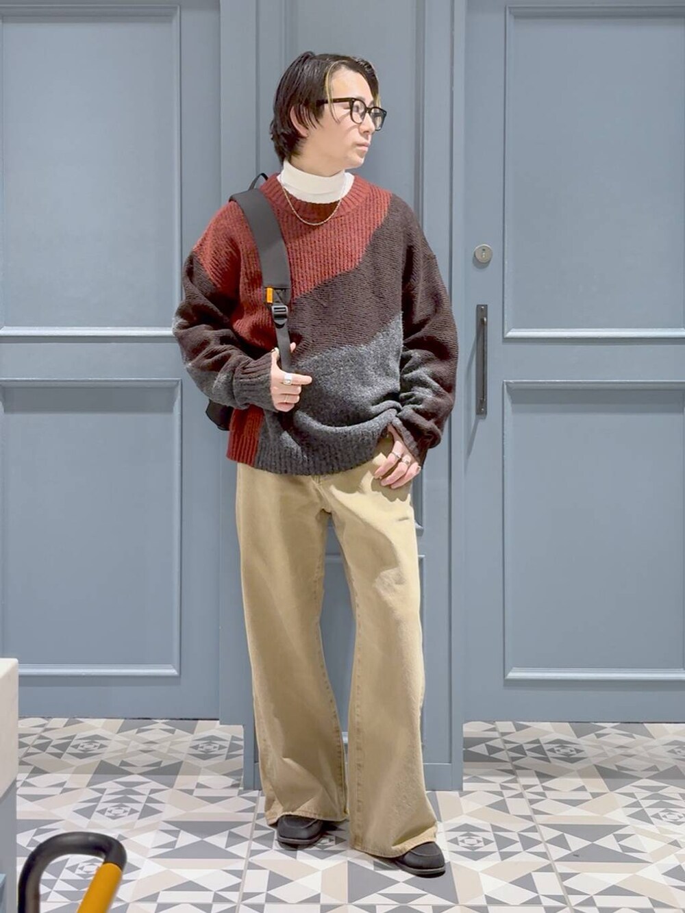 ベージュ系のデニムパンツ、ブラック系のバックパック/リュック、レッド系のニット/セーターを着用したメンズの冬コーディネートの4枚目の写真