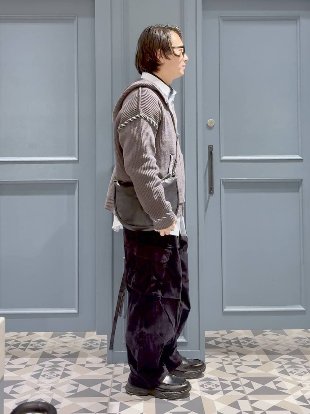 ブラック系のカーゴパンツ、その他のショルダーバッグ、ブラック系のローファーを着用したメンズの冬コーディネートの2枚目の写真