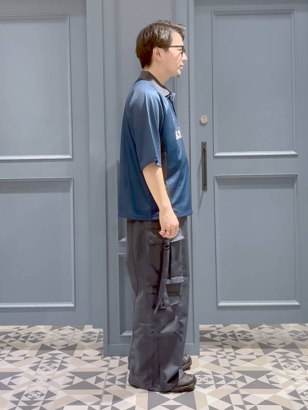 ブルー系のTシャツ/カットソー、グレー系のカーゴパンツ、ブラック系のスニーカーを着用したメンズの秋コーディネートの2枚目の写真