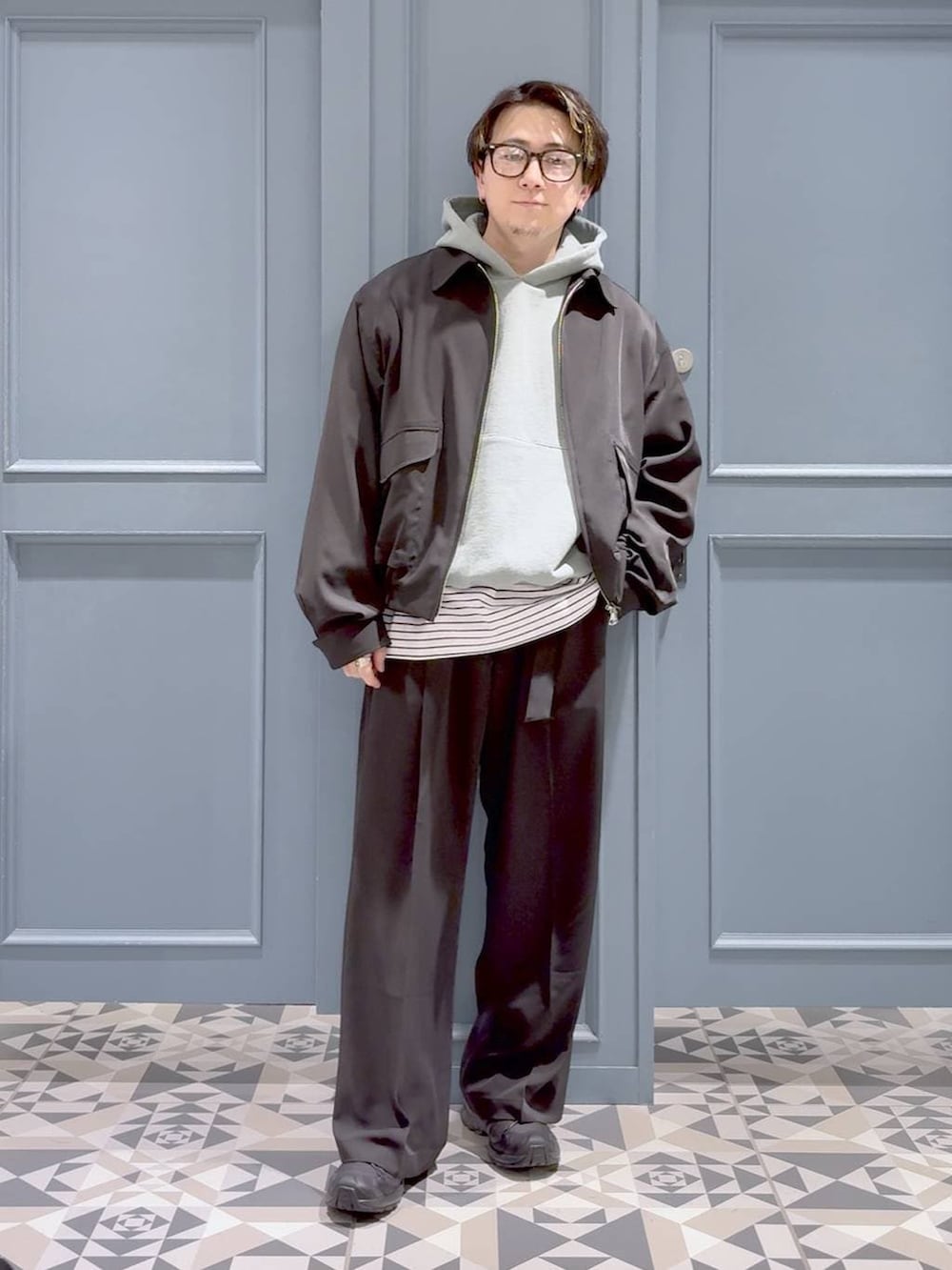 ブラック系のスニーカー、ブラック系のスラックス、グリーン系のパーカーを着用したメンズの春コーディネートの4枚目の写真