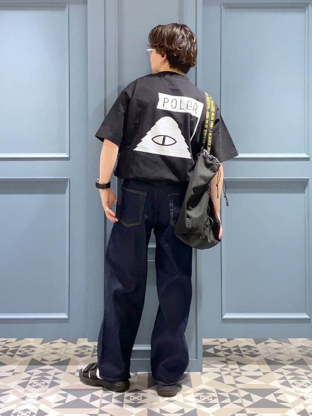 ブルー系のデニムパンツ、ブラック系のサンダル、ブラック系のトートバッグを着用したメンズの春コーディネートの3枚目の写真