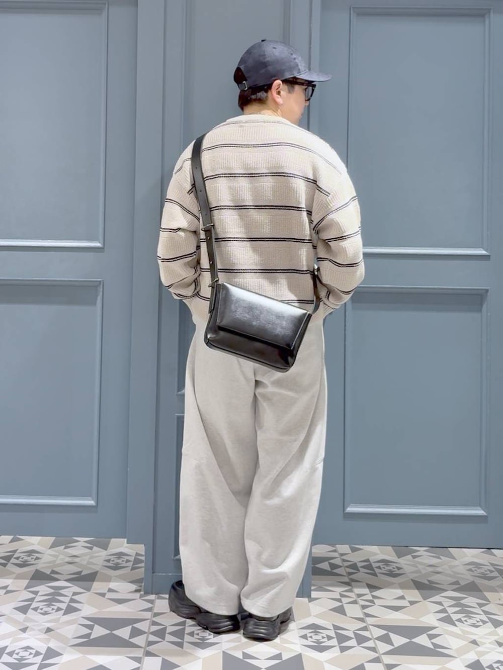 ブラック系のローファー、ブラック系のショルダーバッグ、グレー系のスウェットパンツを着用したメンズの冬コーディネートの3枚目の写真