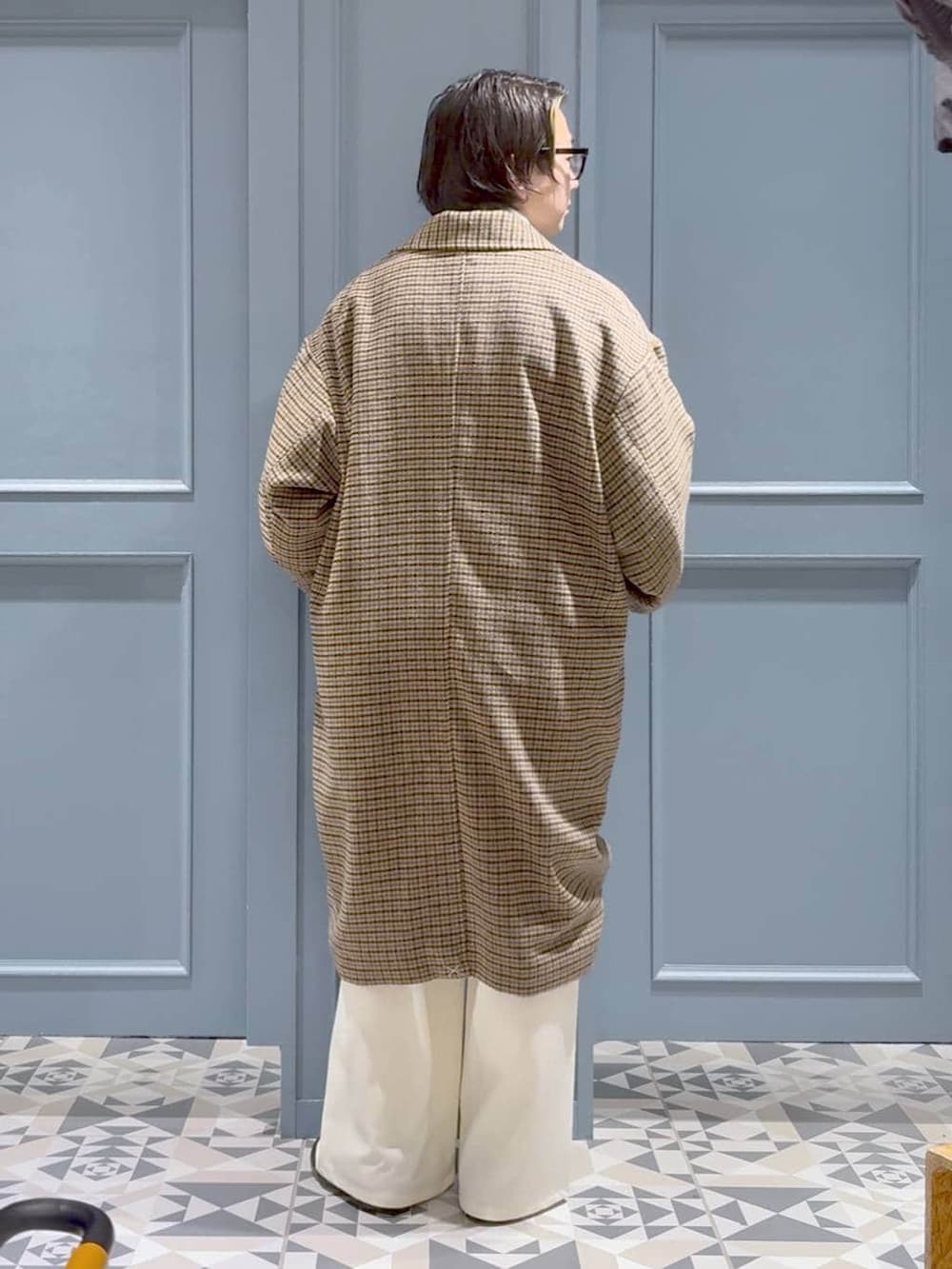 ブラウン系のチェスターコート、レッド系のニット/セーター、ホワイト系のスラックスを着用したメンズの冬コーディネートの3枚目の写真