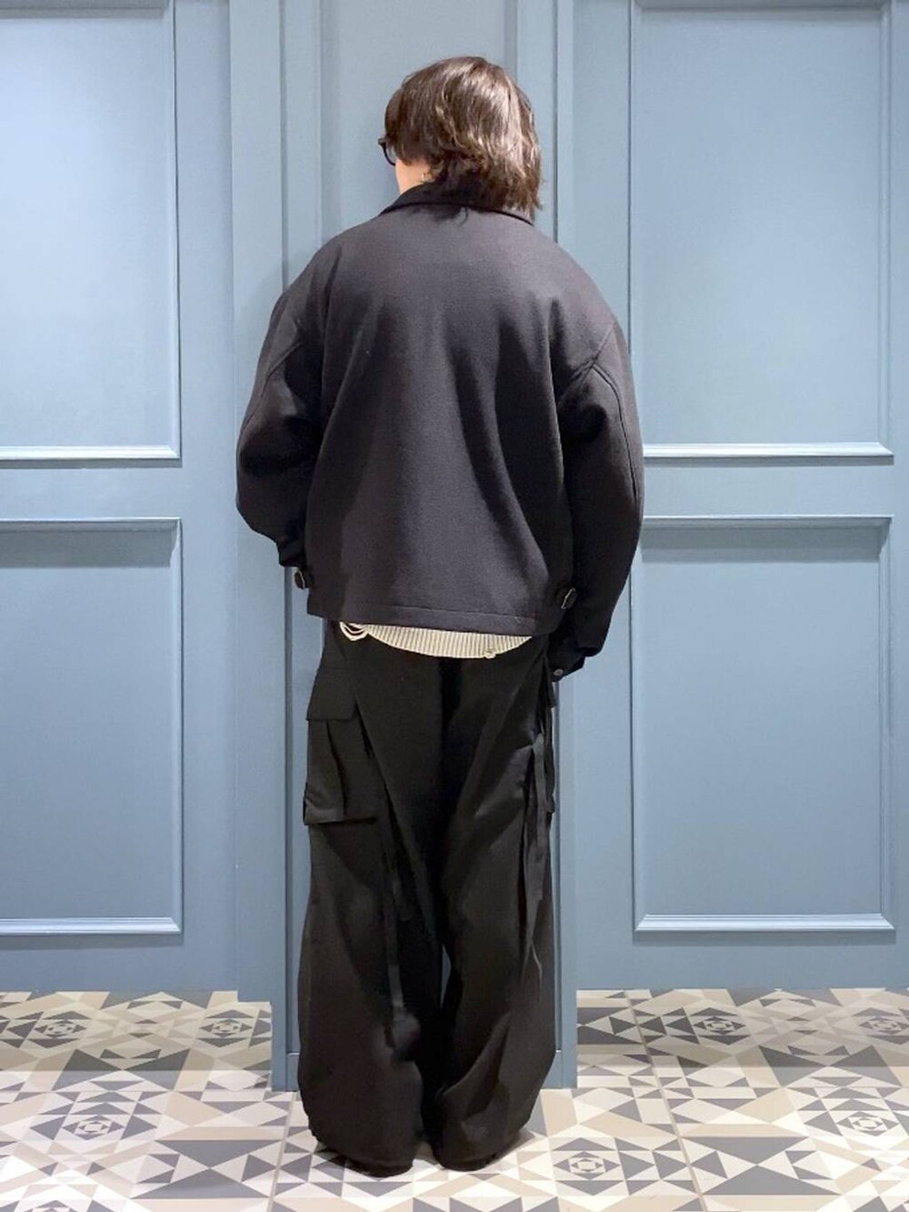 ブラック系のブルゾン、ブラック系のドレスシューズ、ブルー系のニット/セーターを着用したメンズの冬コーディネートの3枚目の写真