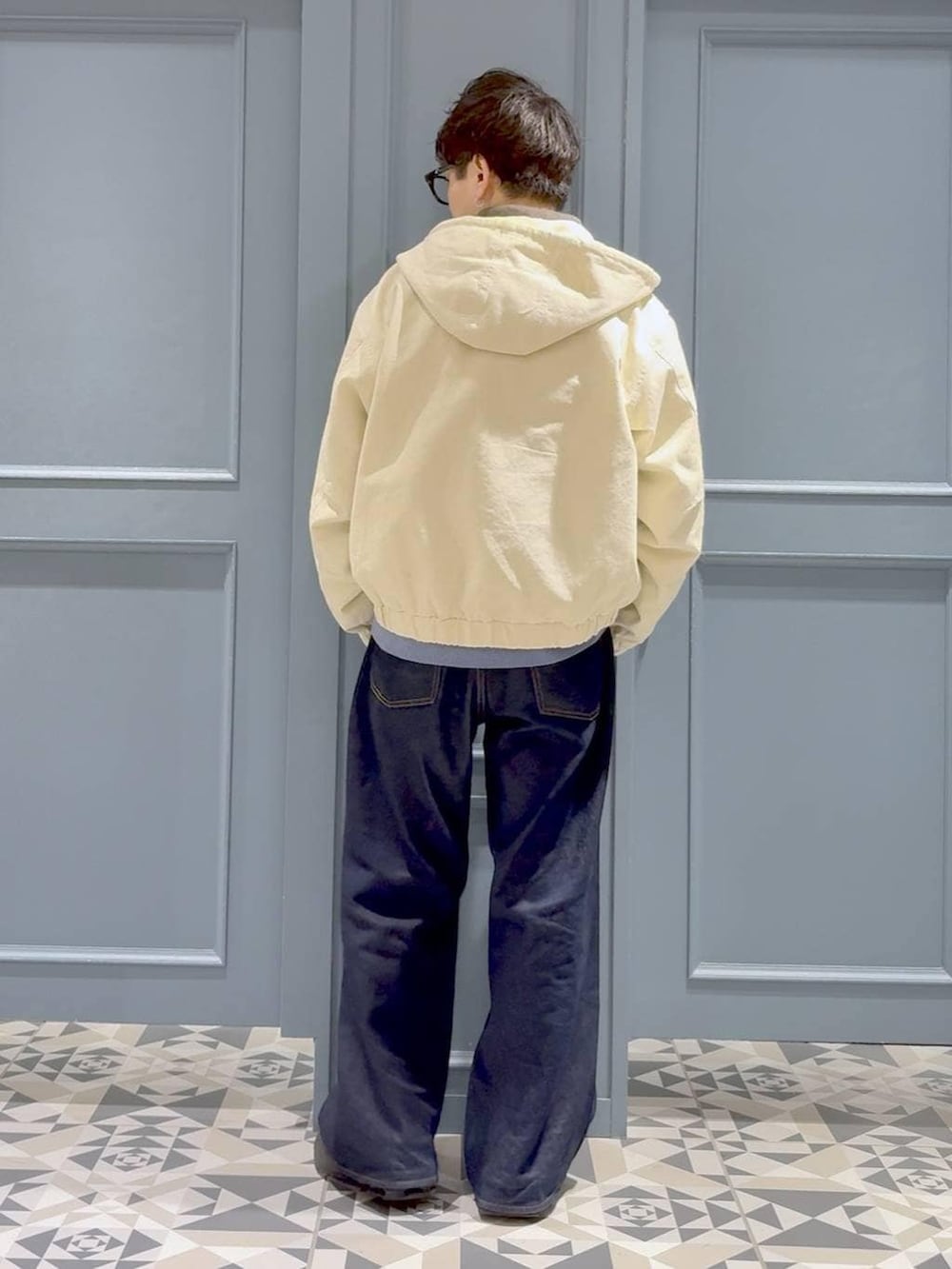 ブルー系のデニムパンツ、ホワイト系のブルゾン、ブルー系のニット/セーターを着用したメンズの冬コーディネートの3枚目の写真