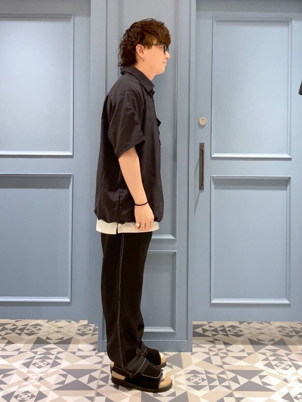 ブラック系のサンダル、ホワイト系のタンクトップ、ブラック系のスラックスを着用したメンズの夏コーディネートの2枚目の写真