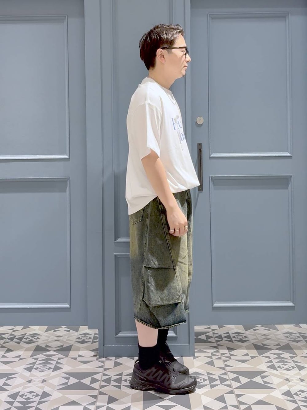 ホワイト系のTシャツ/カットソー、ブルー系のデニムパンツ、ブラック系のスニーカーを着用したメンズの秋コーディネートの2枚目の写真