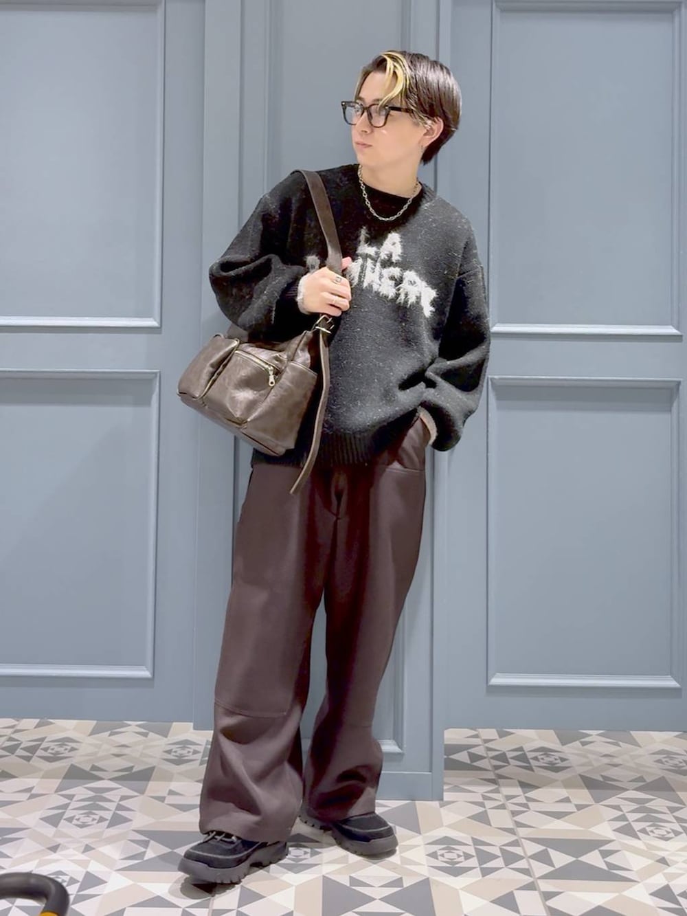 ブラウン系のショルダーバッグ、ブラック系のニット/セーター、ブラウン系のスラックスを着用したメンズの秋コーディネートの4枚目の写真