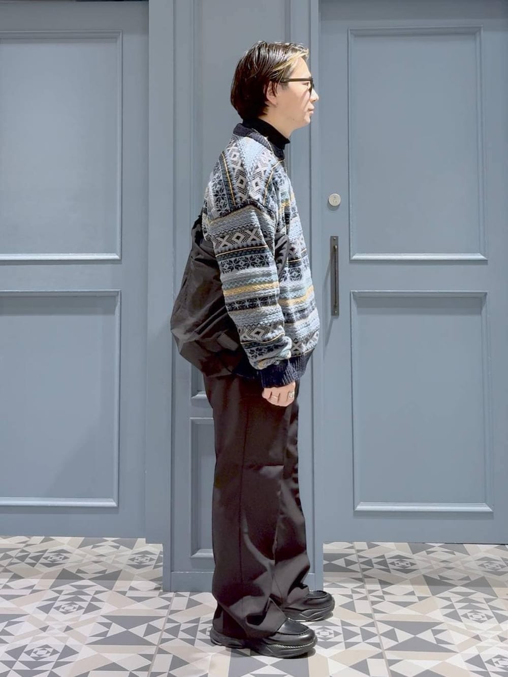 ブラウン系のスラックス、ブラック系のショルダーバッグ、ブラック系のローファーを着用したメンズの冬コーディネートの2枚目の写真