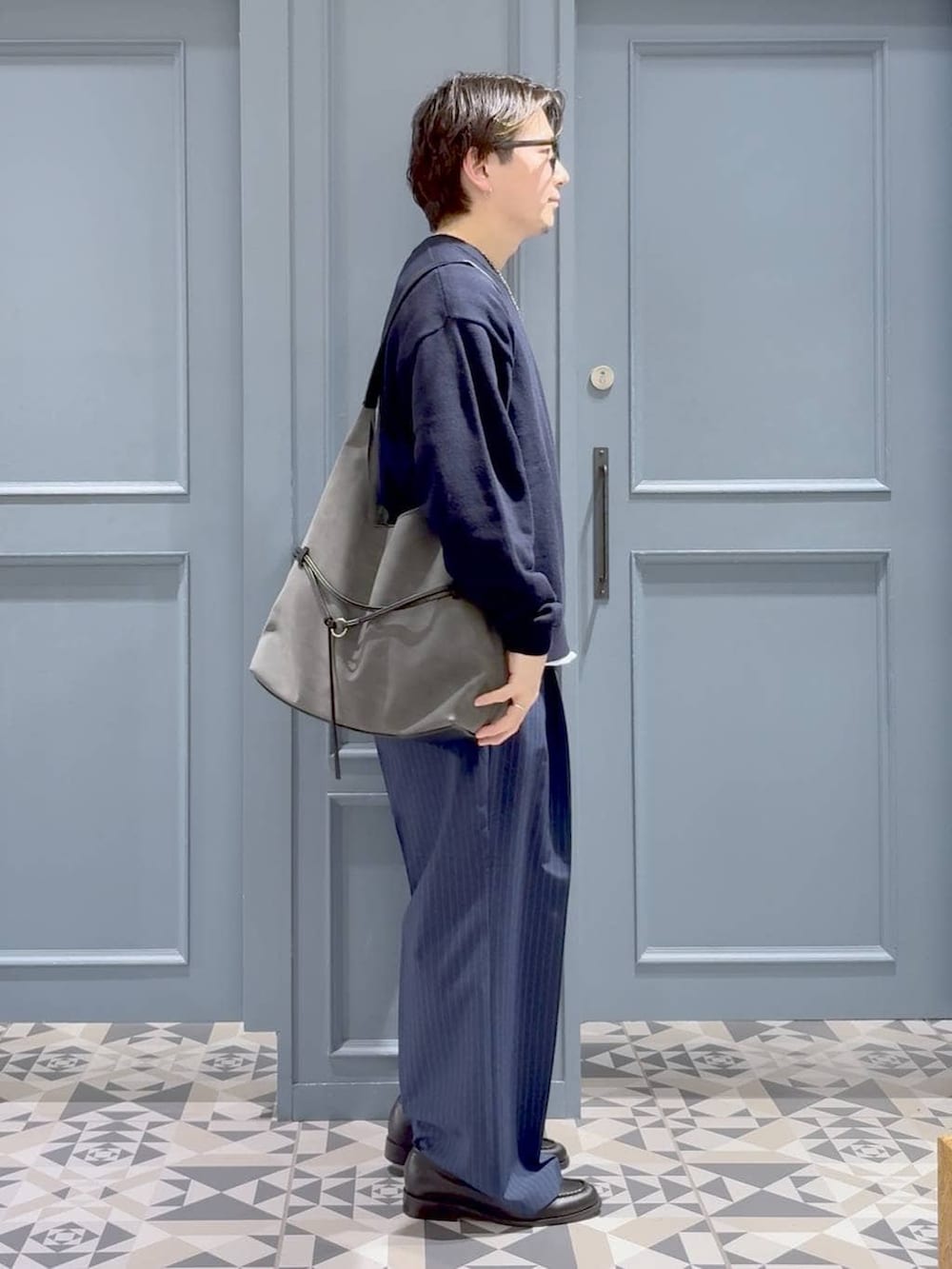 ブルー系のスラックス、ブラック系のローファー、ブルー系のニット/セーターを着用したメンズの春コーディネートの2枚目の写真