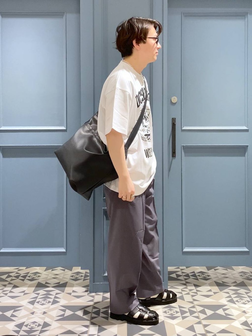 ブラック系のショルダーバッグ、グレー系のスラックス、ブラック系のサンダルを着用したメンズの春コーディネートの2枚目の写真