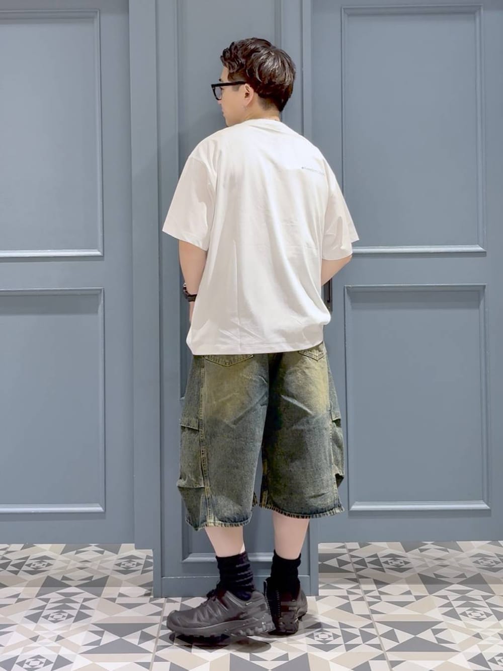 ホワイト系のTシャツ/カットソー、ブルー系のデニムパンツ、ブラック系のスニーカーを着用したメンズの秋コーディネートの3枚目の写真