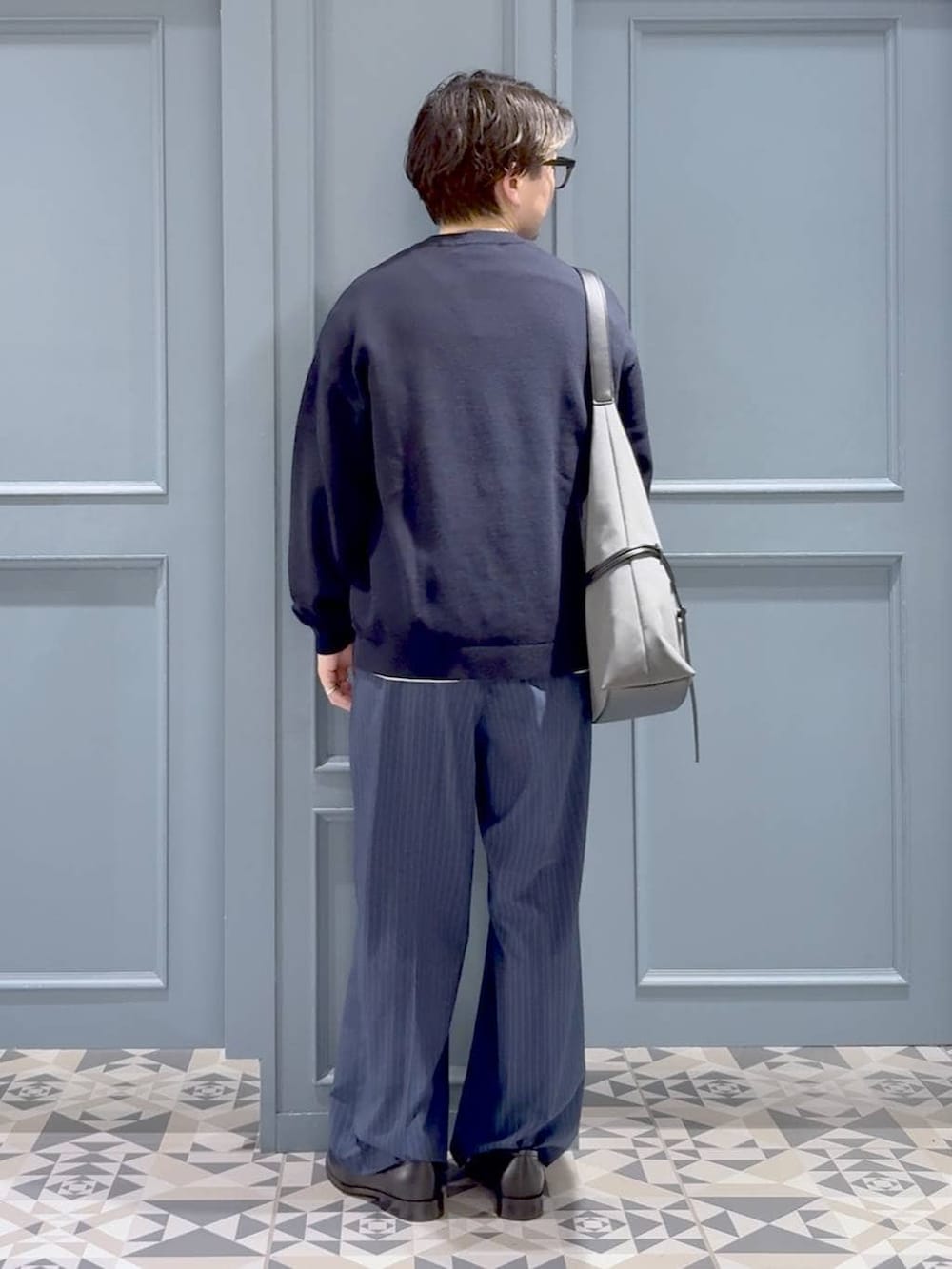 ブルー系のスラックス、ブラック系のローファー、ブルー系のニット/セーターを着用したメンズの春コーディネートの3枚目の写真