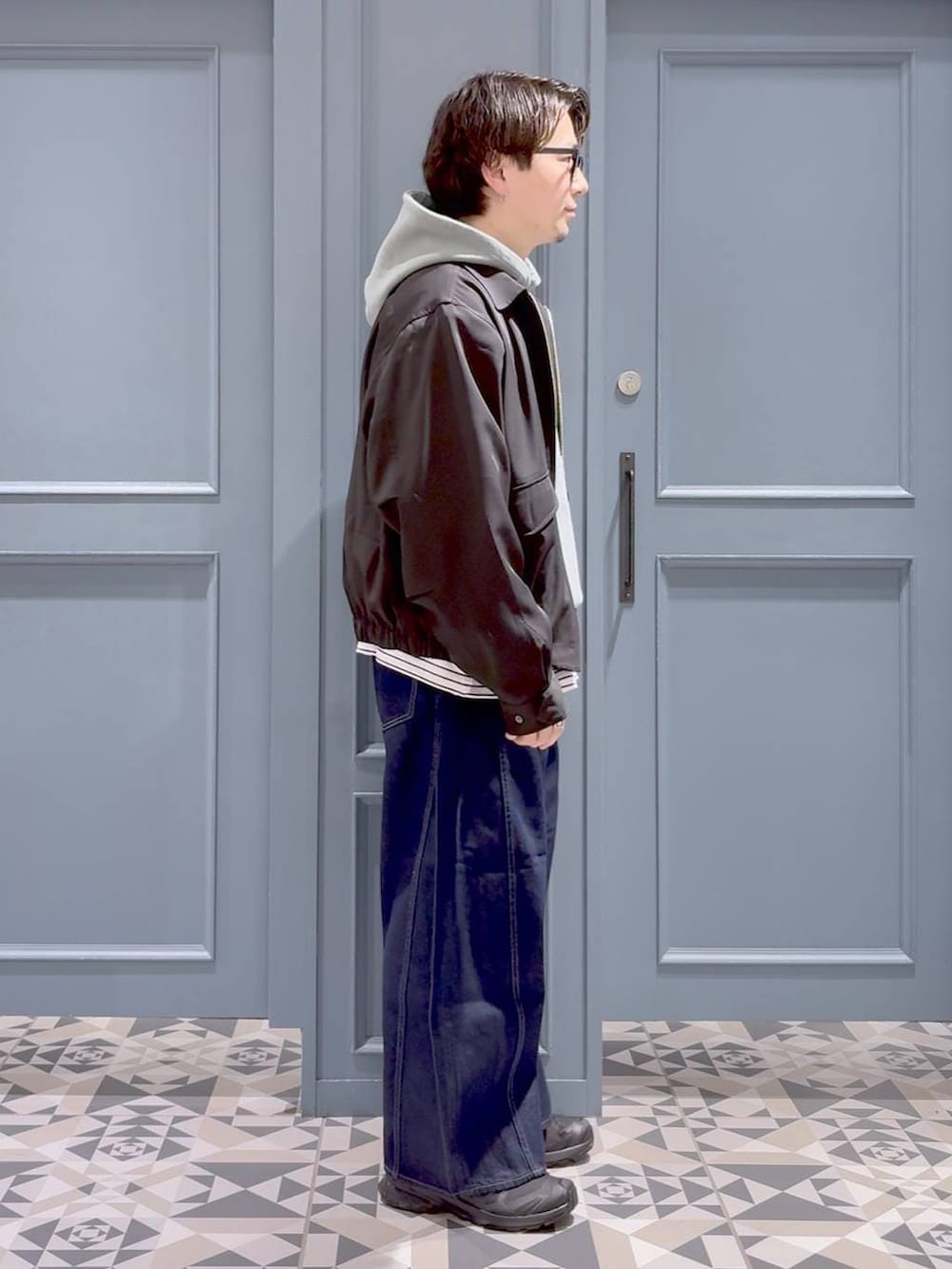 ブラック系のスニーカー、グリーン系のパーカー、ブラック系のブルゾンを着用したメンズの春コーディネートの2枚目の写真