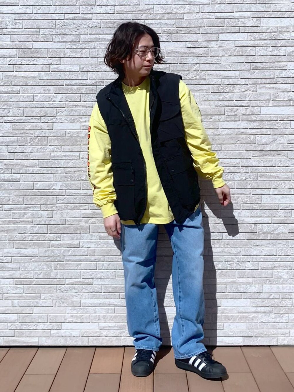 イエロー系のTシャツ/カットソー、ブルー系のデニムパンツ、ブラック系のナイロンジャケットを着用したメンズの春コーディネートの4枚目の写真