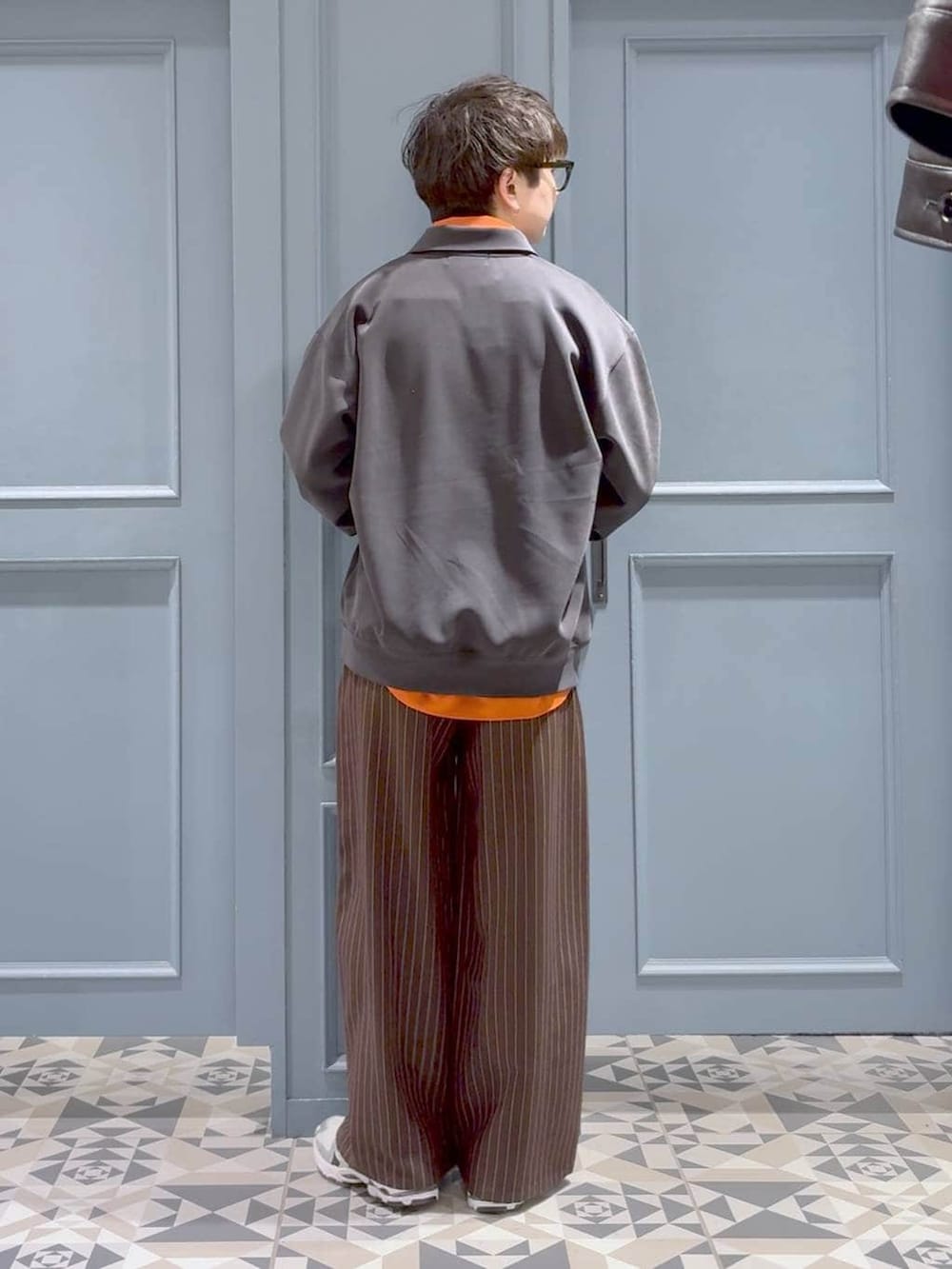 オレンジ系のシャツ/ブラウス、ブラウン系のスラックス、ブラック系のスウェットを着用したメンズの冬コーディネートの3枚目の写真