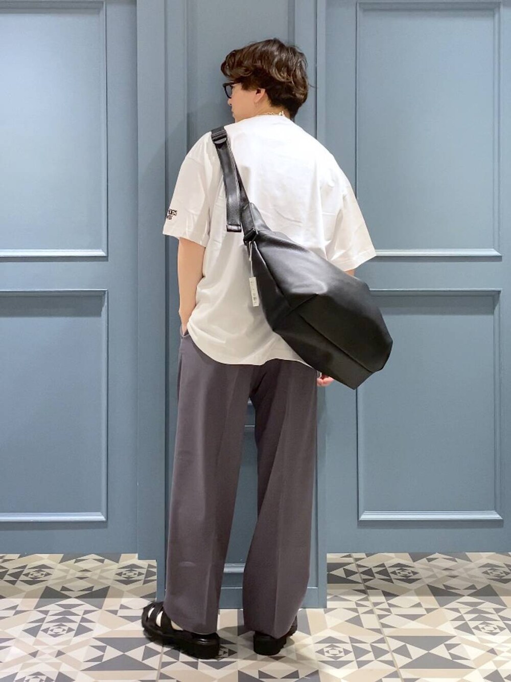 ブラック系のショルダーバッグ、グレー系のスラックス、ブラック系のサンダルを着用したメンズの春コーディネートの3枚目の写真