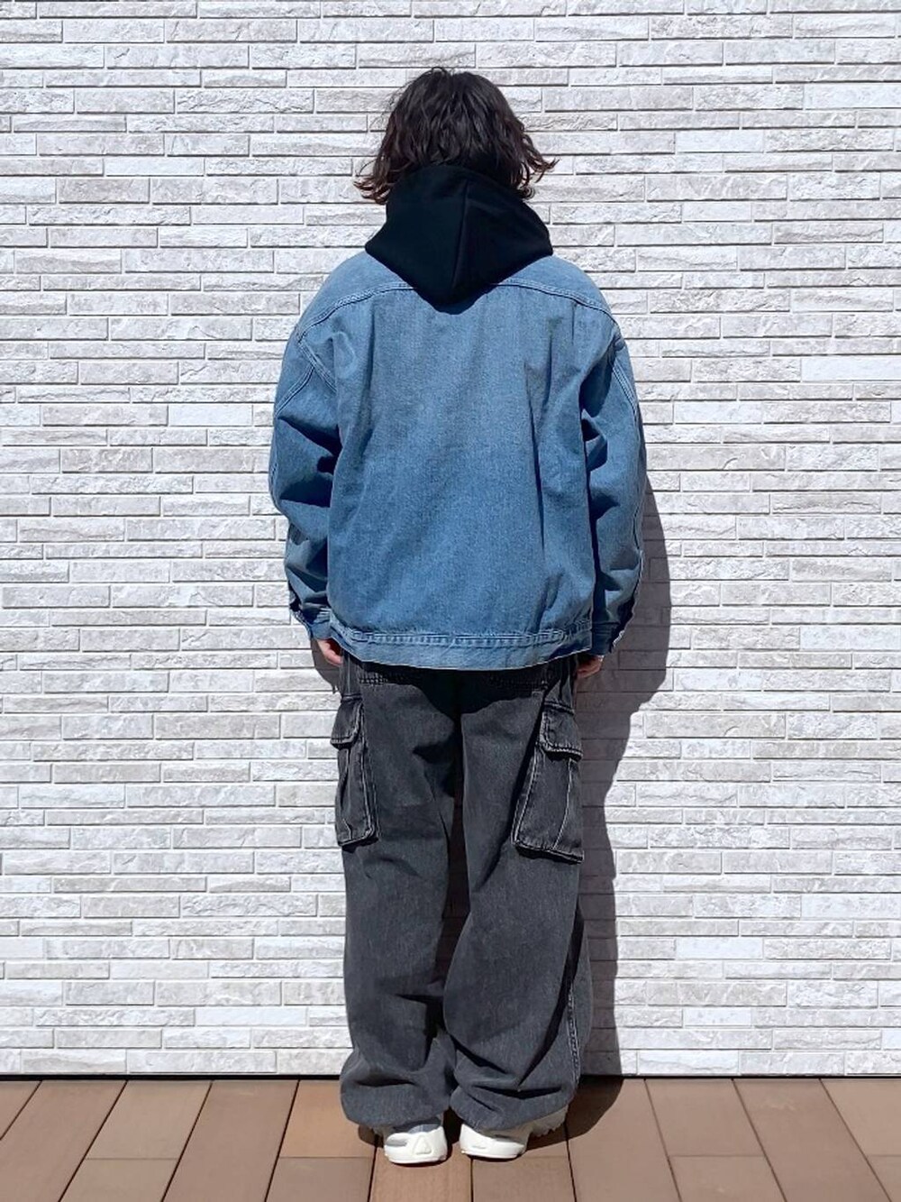 グレー系のデニムパンツ、ブルー系のデニムジャケット、ブラック系のパーカーを着用したメンズの春コーディネートの3枚目の写真