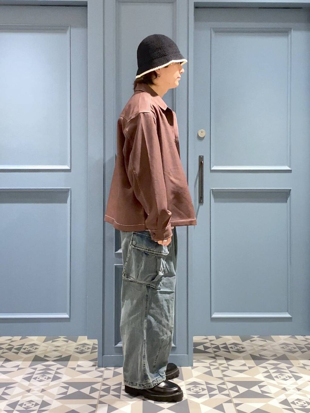 ブルー系のデニムパンツ、ブラウン系のブルゾン、ブラック系のドレスシューズを着用したメンズの秋コーディネートの2枚目の写真