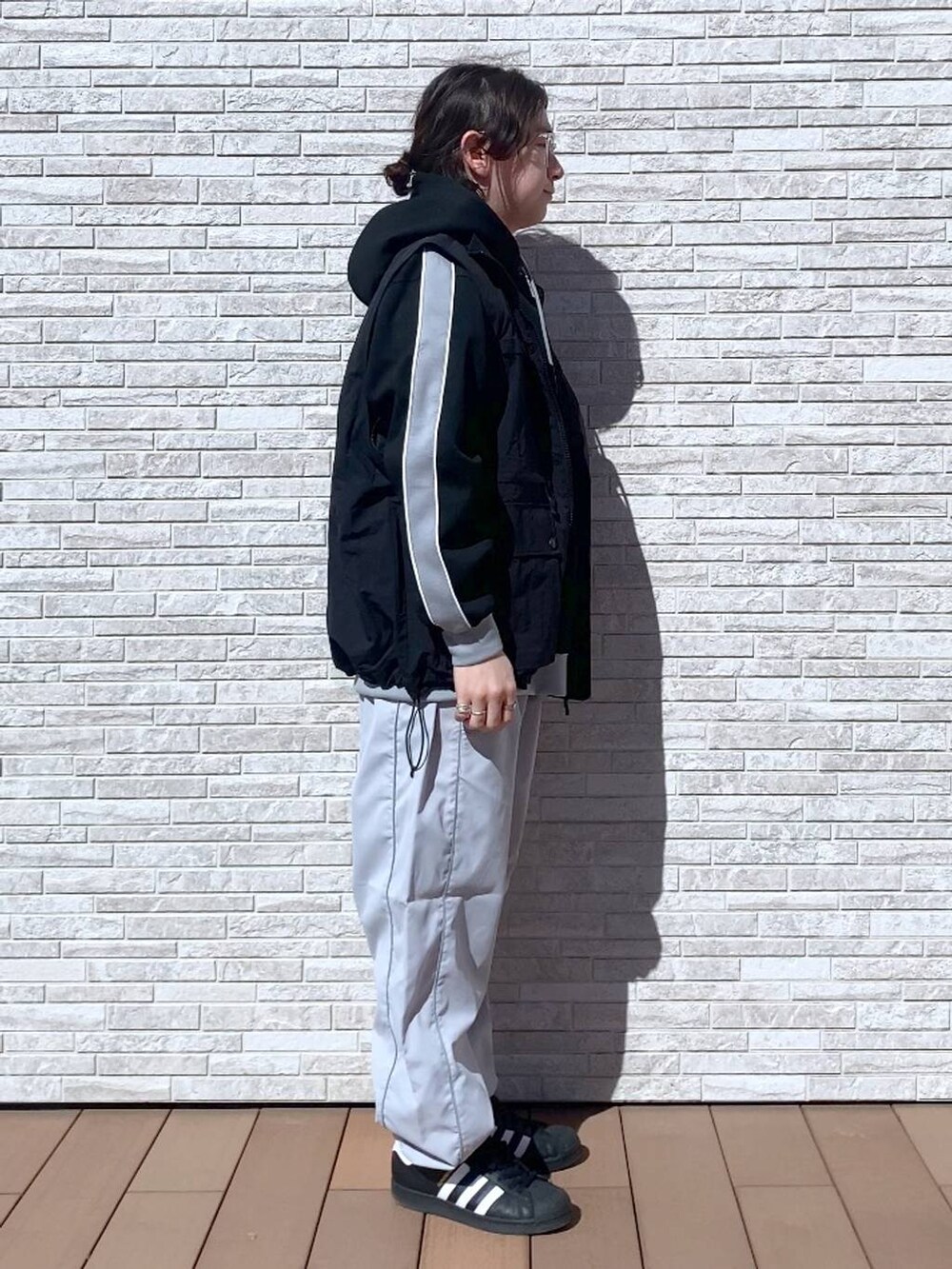 ブラック系のパーカー、ブラック系のナイロンジャケット、ホワイト系のスウェットパンツを着用したメンズの春コーディネートの2枚目の写真