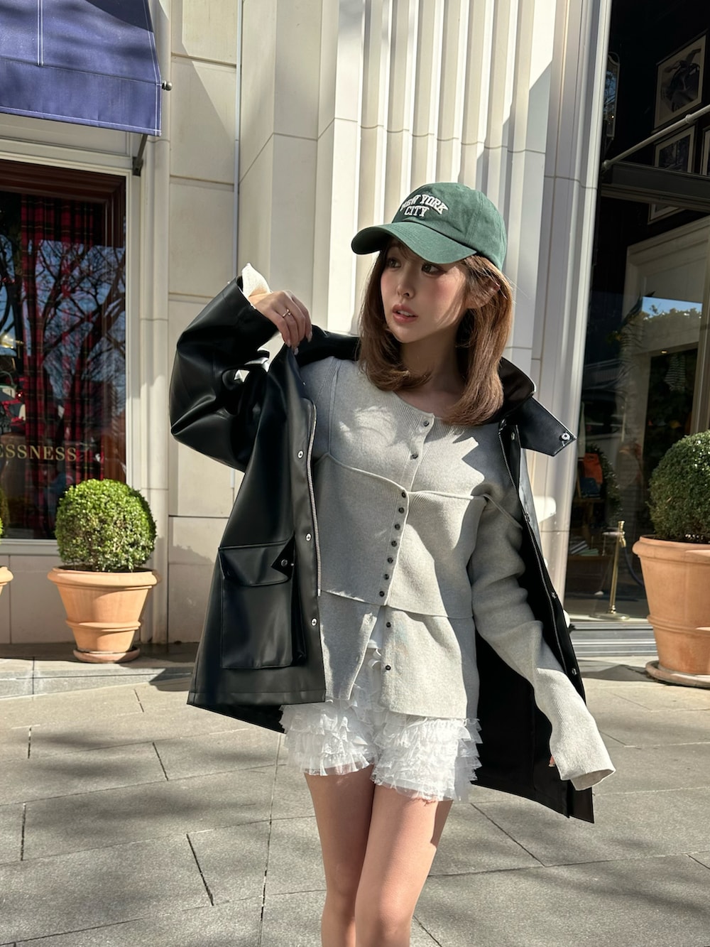 ブラック系のテーラードジャケット、ブラック系のスニーカー、ホワイト系のカーディガン/ボレロを着用したレディースの冬コーディネートの3枚目の写真