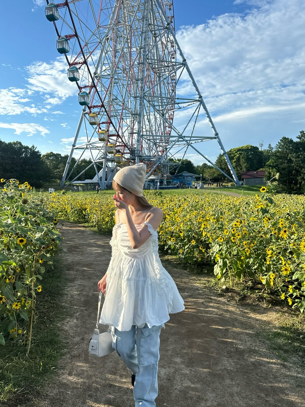 ホワイト系のチュニック、ブルー系のパンツ、ホワイト系のショルダーバッグを着用したレディースの夏コーディネートの4枚目の写真