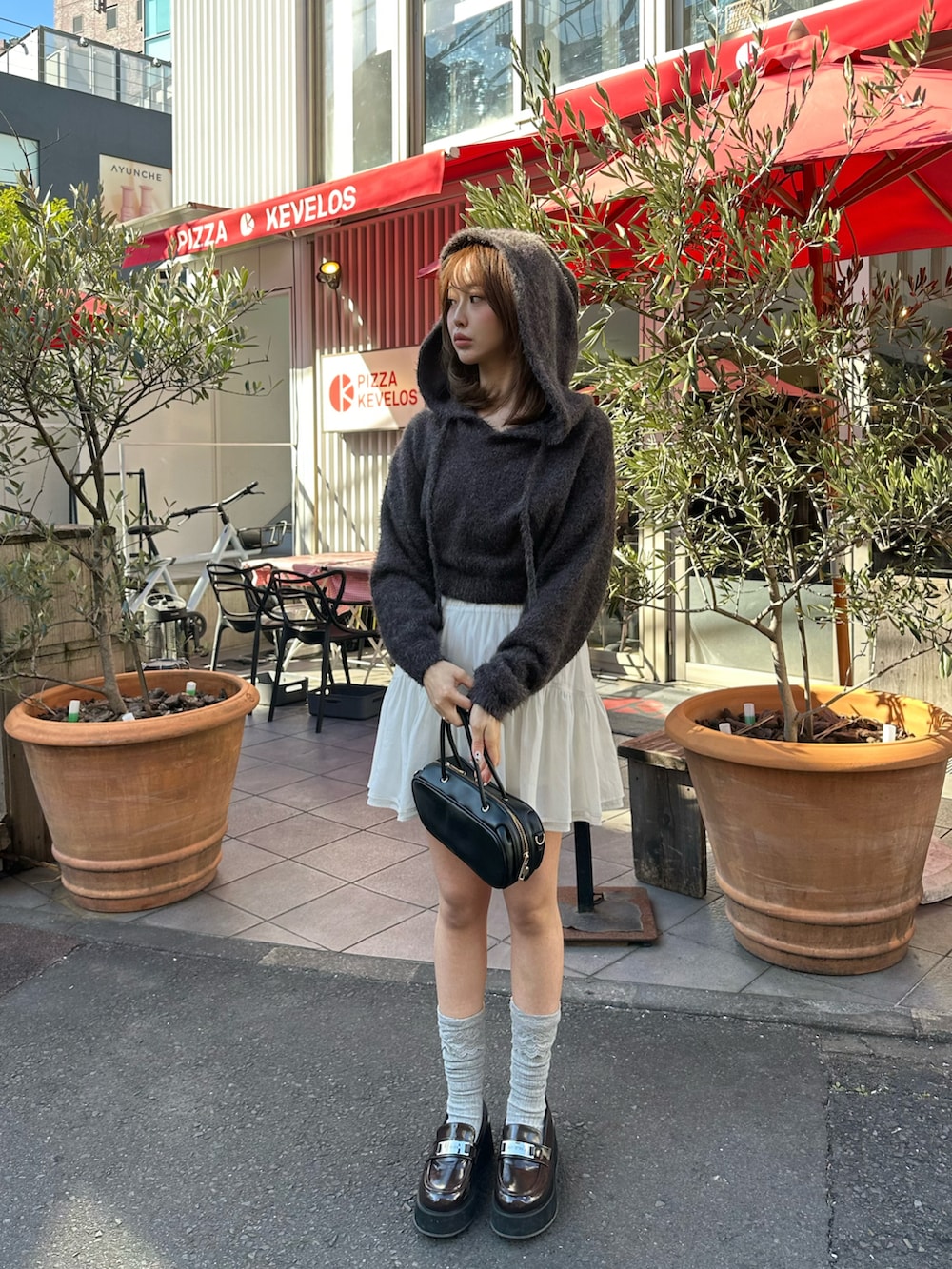 ブラック系のニット/セーター、ホワイト系のスカート、ブラック系のボストンバッグを着用したレディースの冬コーディネートの4枚目の写真