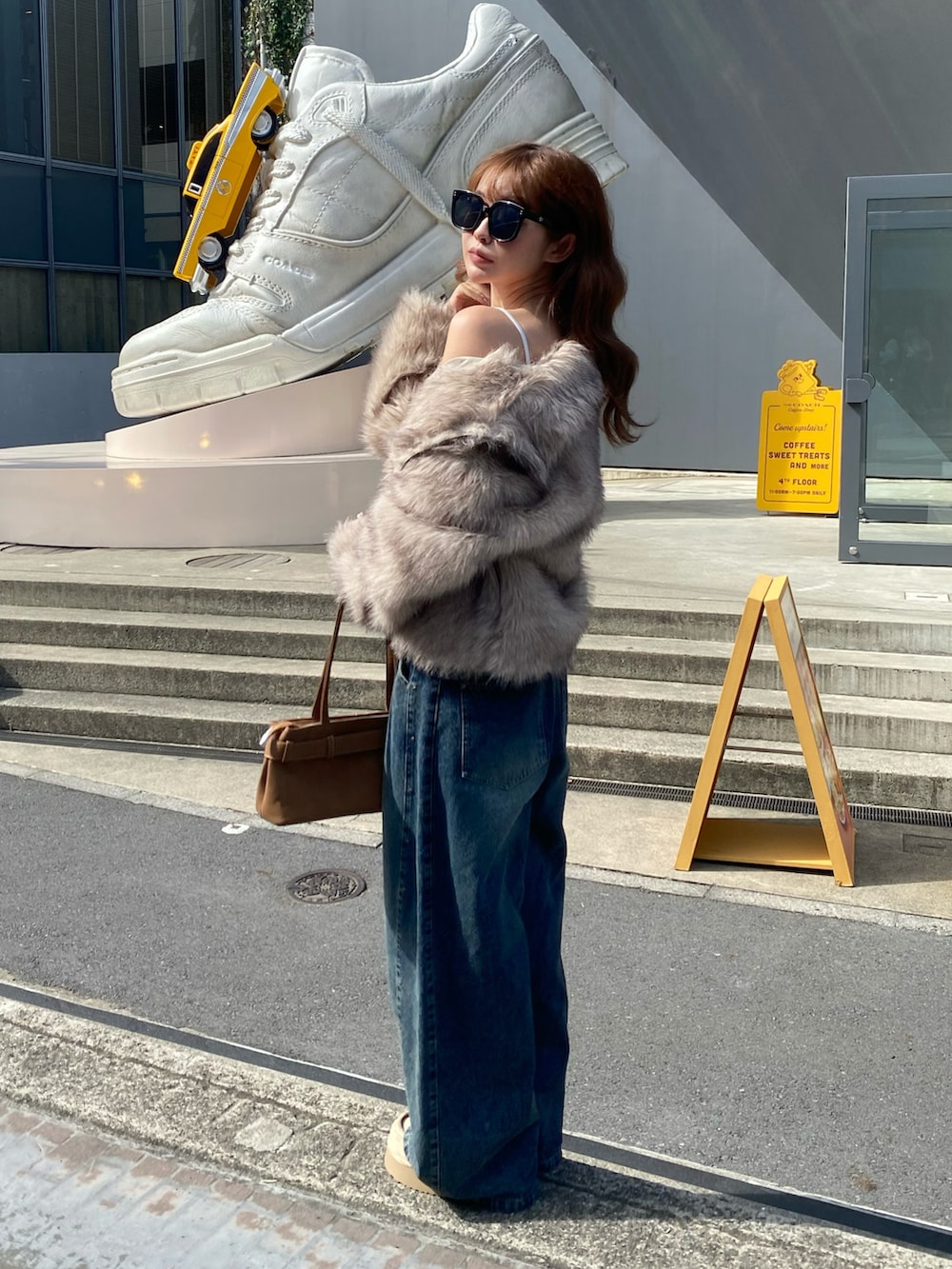 ホワイト系のブルゾン、ブラック系のショルダーバッグ、ブルー系のデニムパンツを着用したレディースの秋コーディネートの2枚目の写真