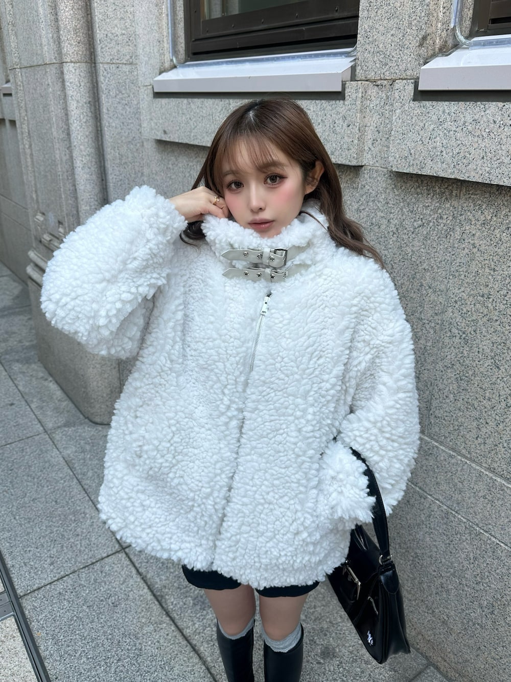 ホワイト系のジャケット/アウター、ブラック系のブーツ、ブラック系のバッグを着用したレディースの冬コーディネートの2枚目の写真