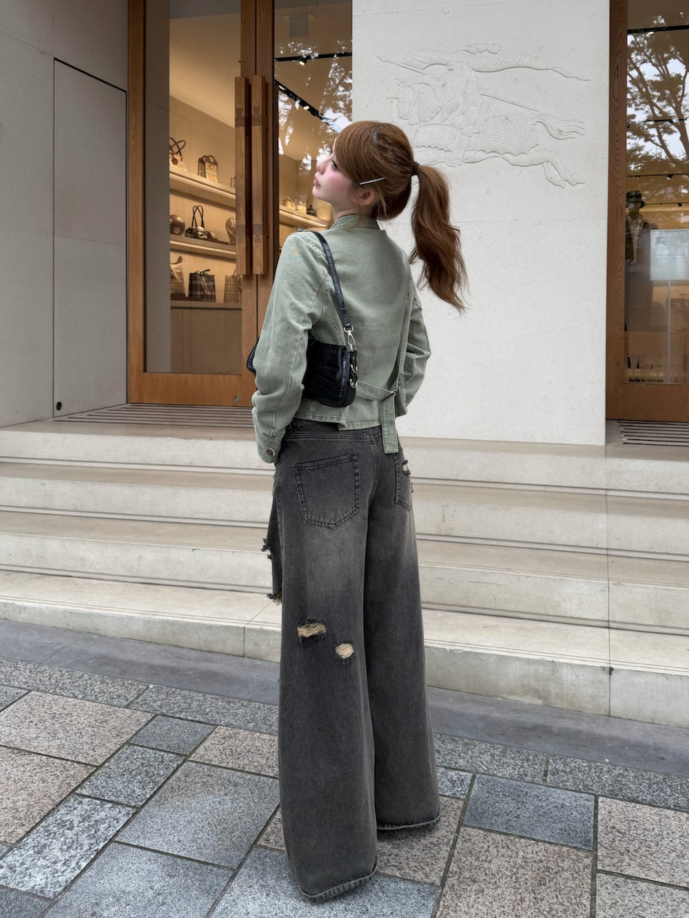 グレー系のデニムパンツ、ベージュ系のキャミソール、グリーン系のデニムジャケットを着用したレディースの秋コーディネートの2枚目の写真