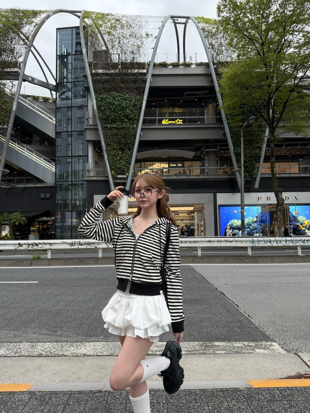 ホワイト系のパーカー、ホワイト系のスカート、ブラック系のスニーカーを着用したレディースの春コーディネートの2枚目の写真