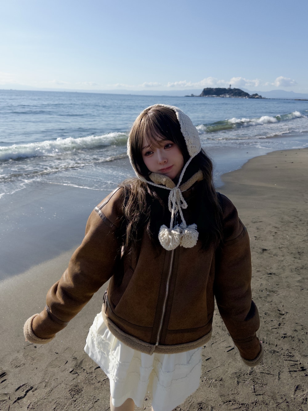 ブラウン系のジャケット/アウター、ホワイト系のスカート、ブラック系のブーツを着用したレディースの冬コーディネートの2枚目の写真