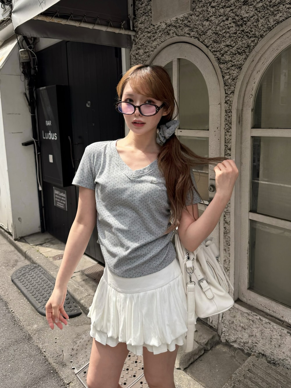ホワイト系のスカート、グレー系のTシャツ/カットソー、ブラック系のショルダーバッグを着用したレディースの春コーディネートの2枚目の写真