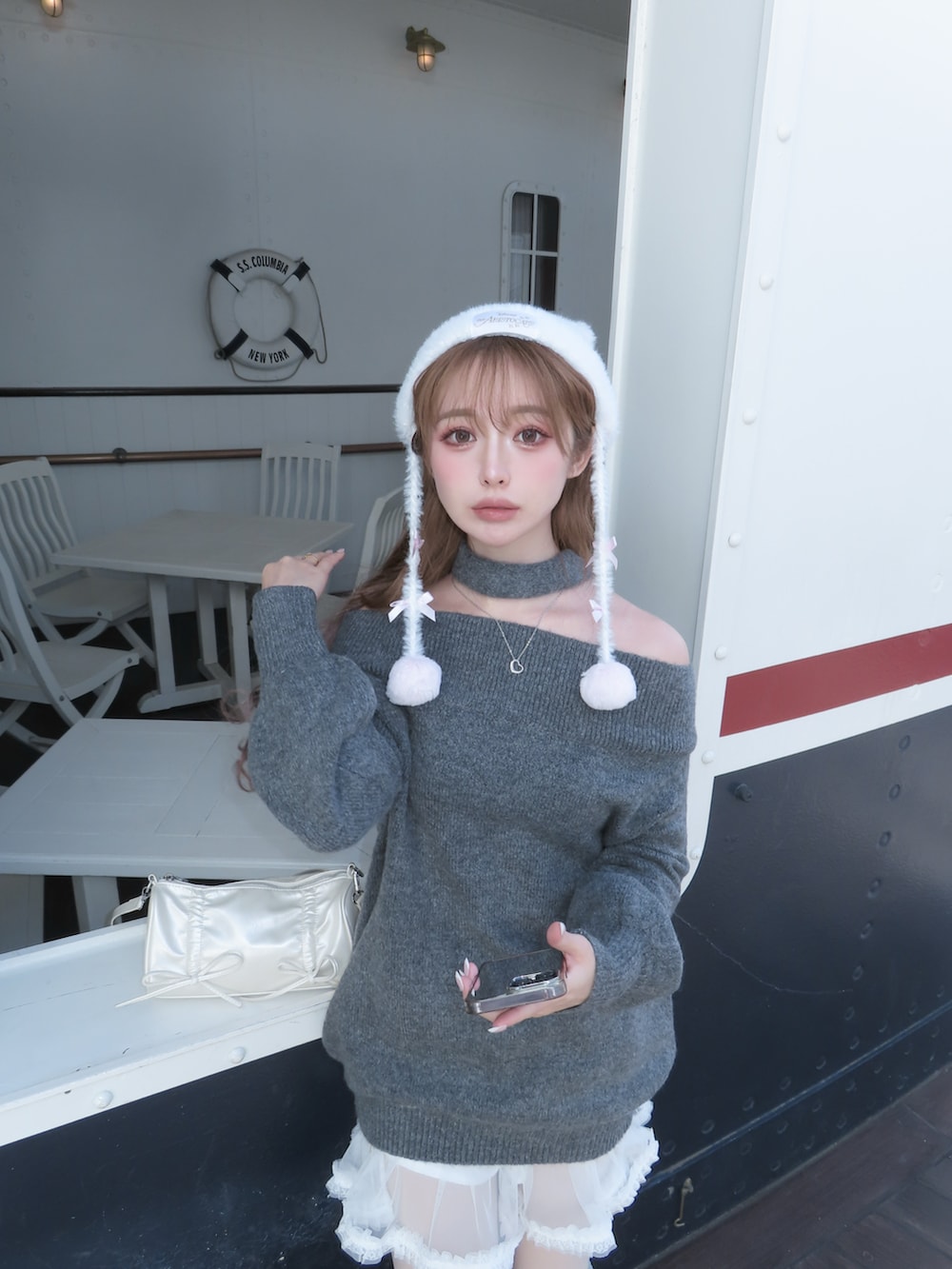 グレー系のニット/セーター、ブラック系のブーツ、ホワイト系のジャケット/アウターを着用したレディースの冬コーディネートの3枚目の写真