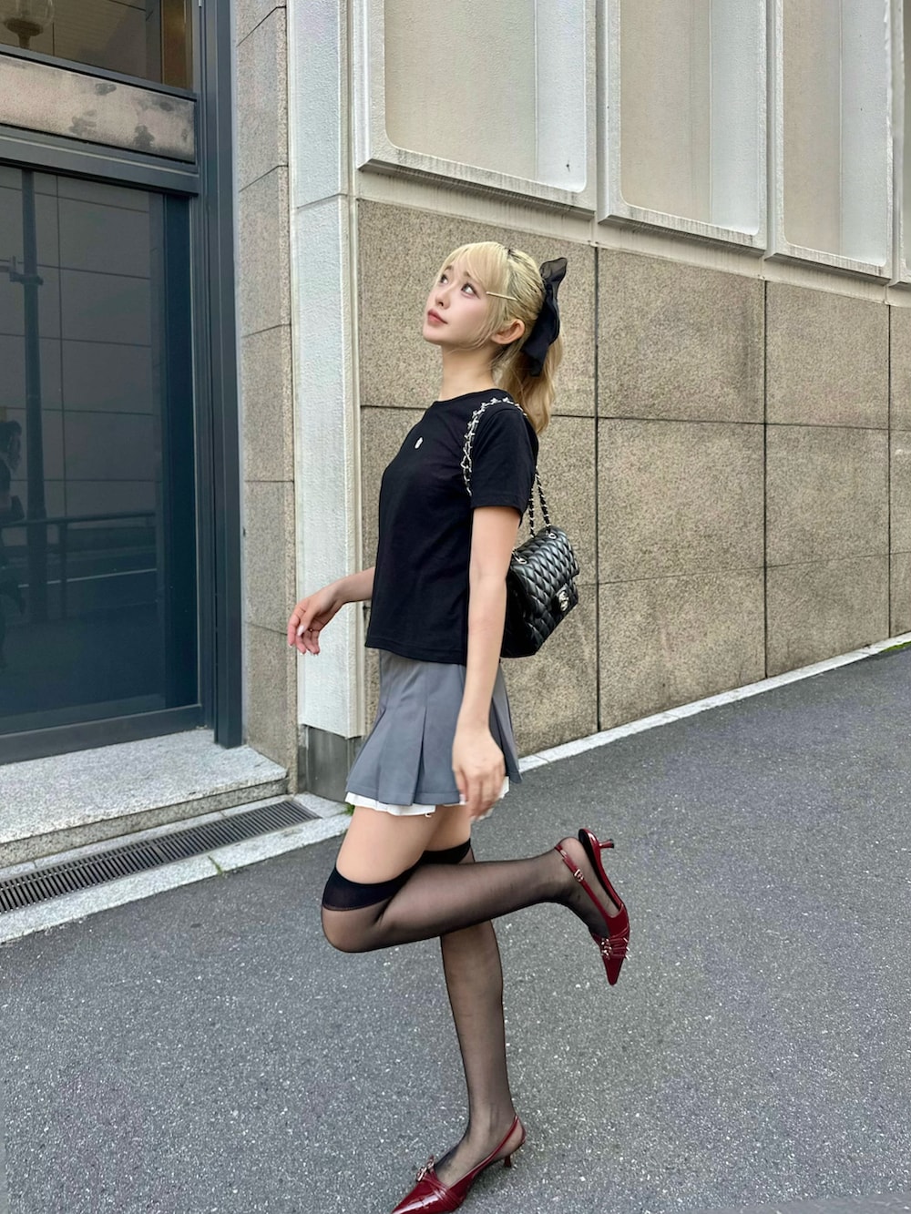 グレー系のスカート、レッド系のシューズ、ブラック系のTシャツ/カットソーを着用したレディースの夏コーディネートの2枚目の写真