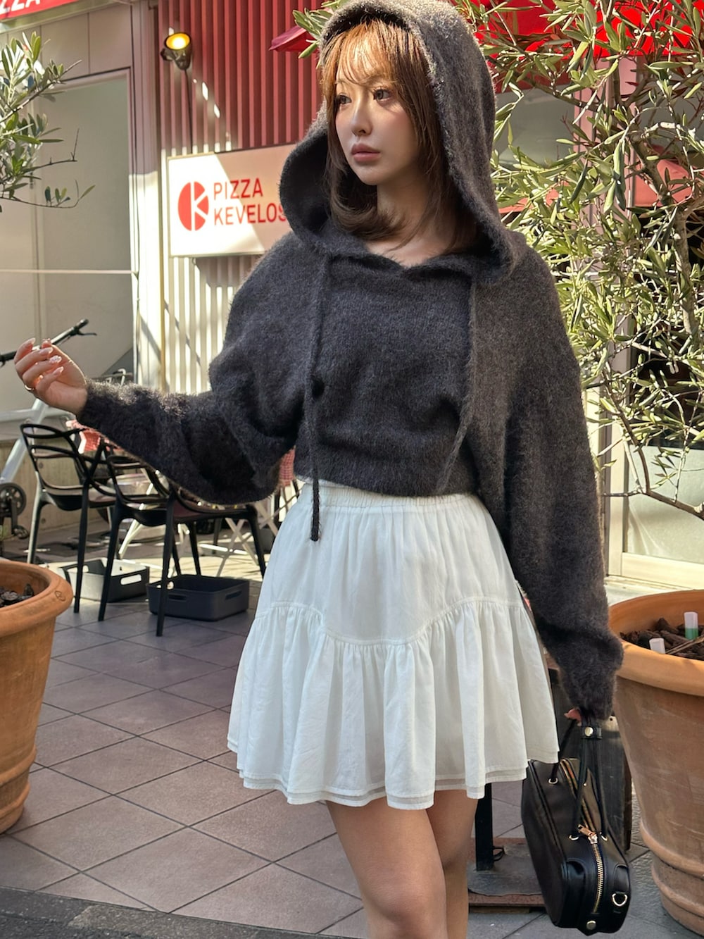 ブラック系のニット/セーター、ホワイト系のスカート、ブラック系のボストンバッグを着用したレディースの冬コーディネートの3枚目の写真