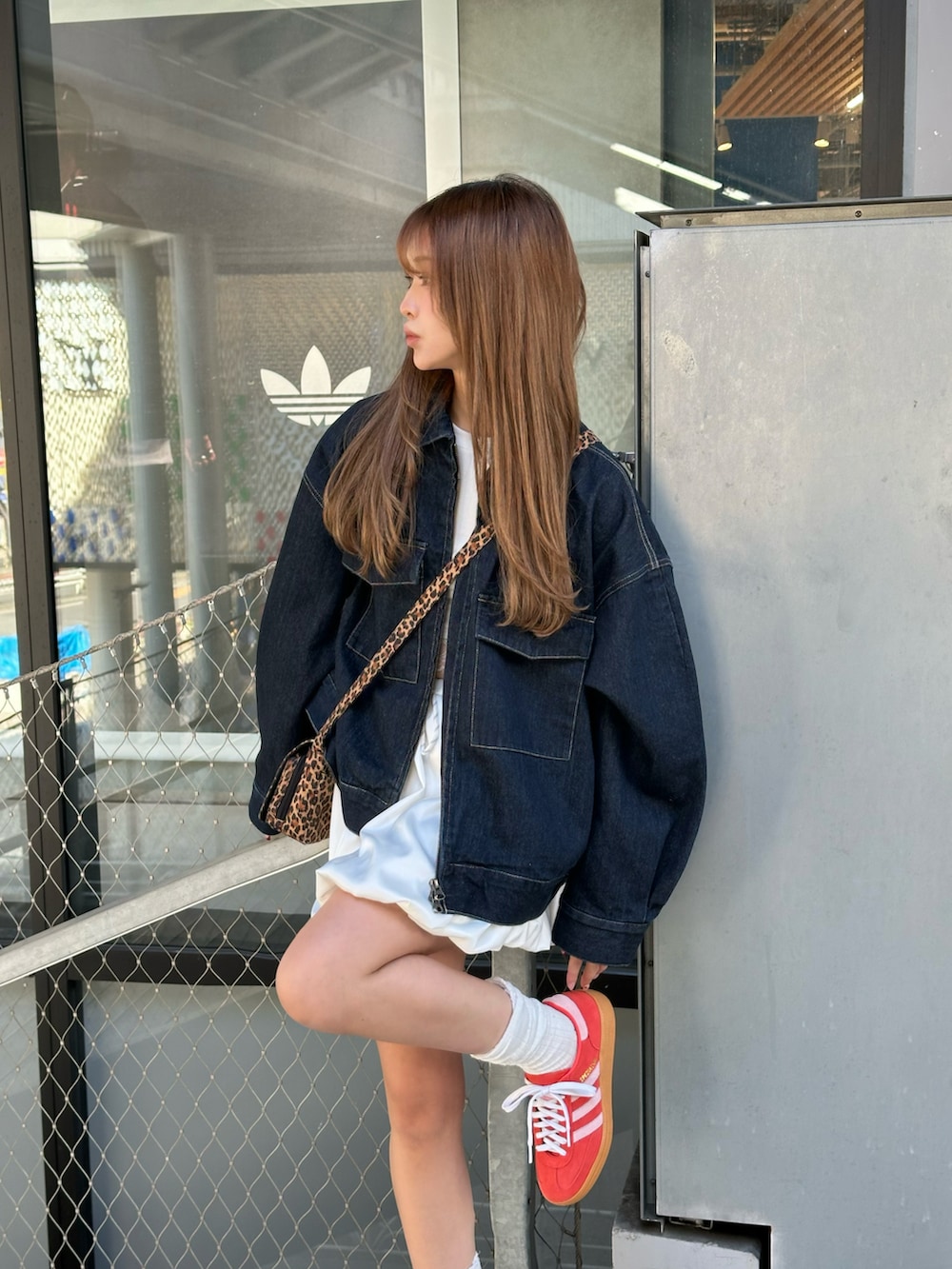 ブルー系のデニムジャケット、ホワイト系のスカート、レッド系のスニーカーを着用したレディースの春コーディネートの2枚目の写真