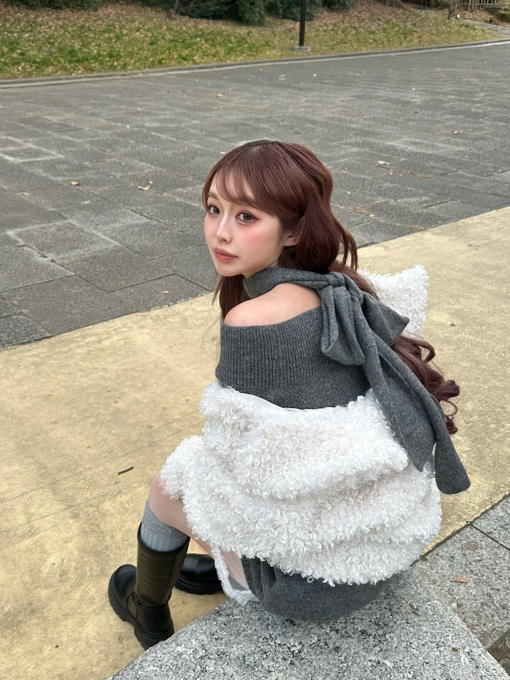 グレー系のニット/セーター、ブラック系のブーツ、ホワイト系のジャケット/アウターを着用したレディースの冬コーディネートの2枚目の写真